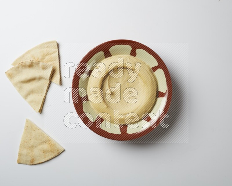 Plain hummus in a traditional plate on a white background