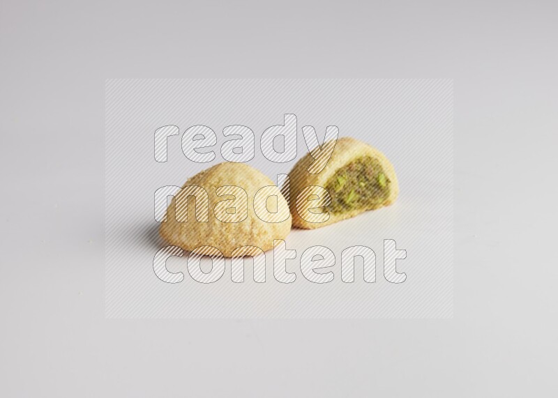 Two Pieces of Maamoul filled with pistachio paste  one of them is cut direct on white background