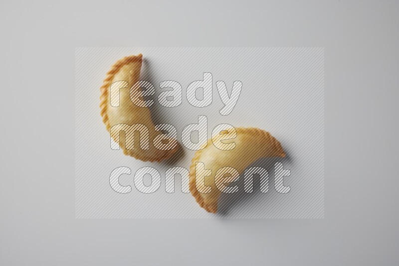 Two fried sambosa from a top angle on a white background