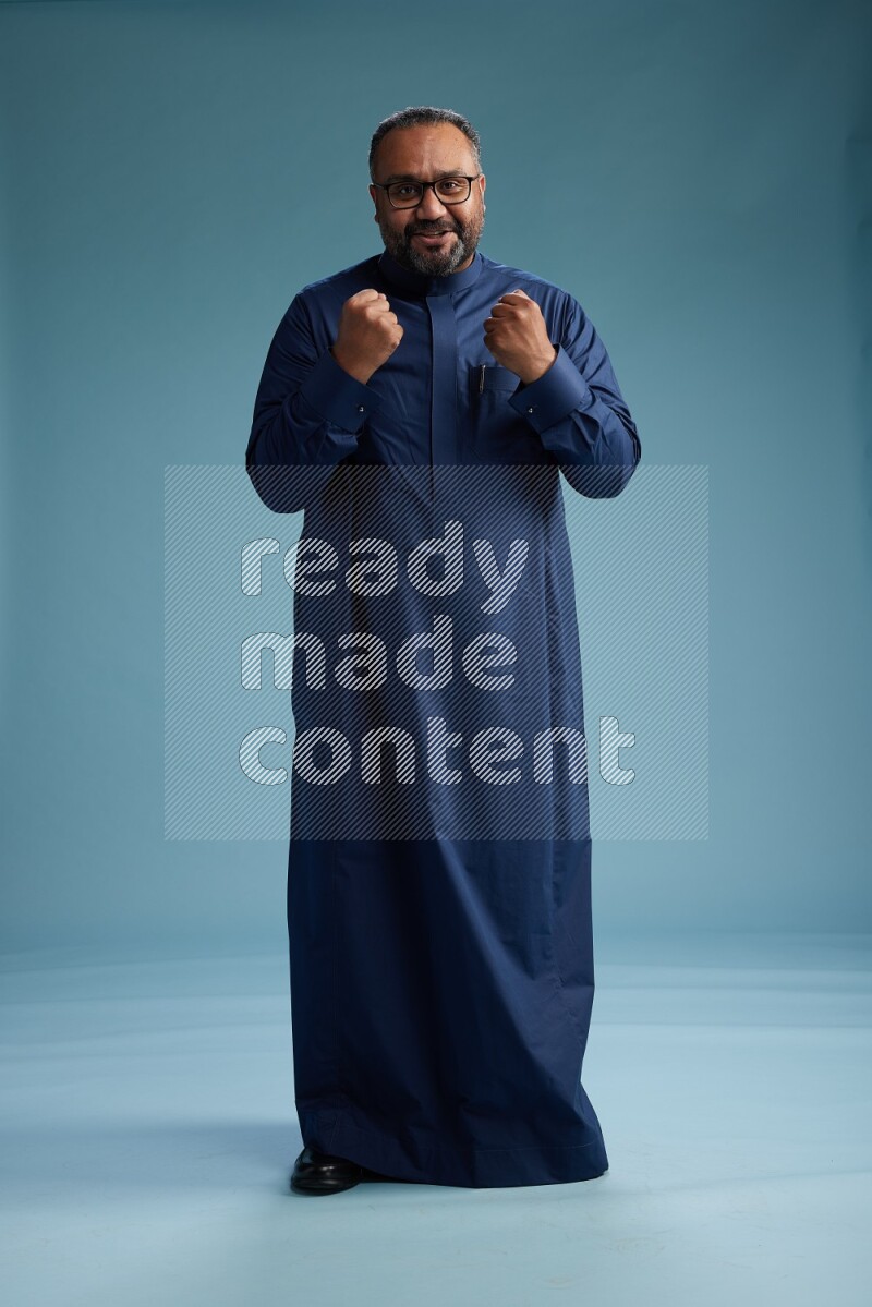 Saudi Man without shimag Standing Interacting with the camera on blue background