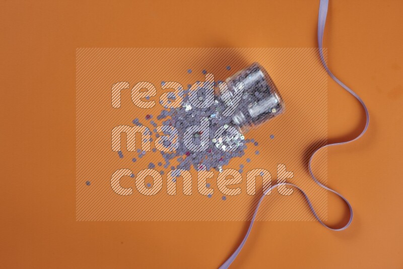 A purple collection of sewing and tailoring tools arranged on a orange background