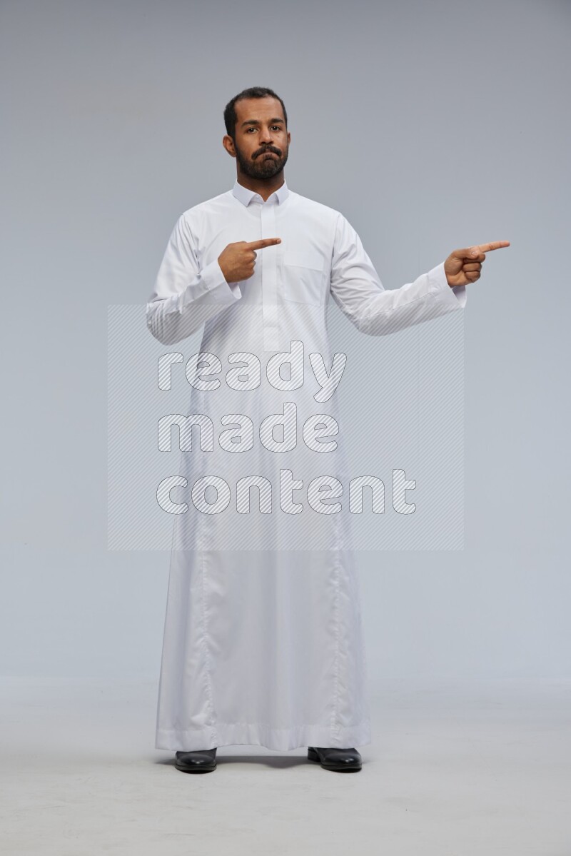 Saudi man Wearing Thob standing interacting with the camera on Gray background