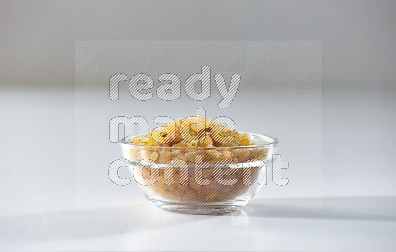 A glass bowl full of raisins on a white background in different angles