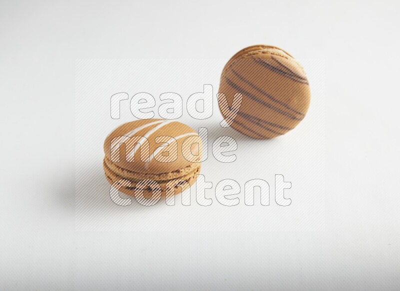 45º Shot of of two assorted Brown Irish Cream, and light brown  Almond Cream macarons on white background