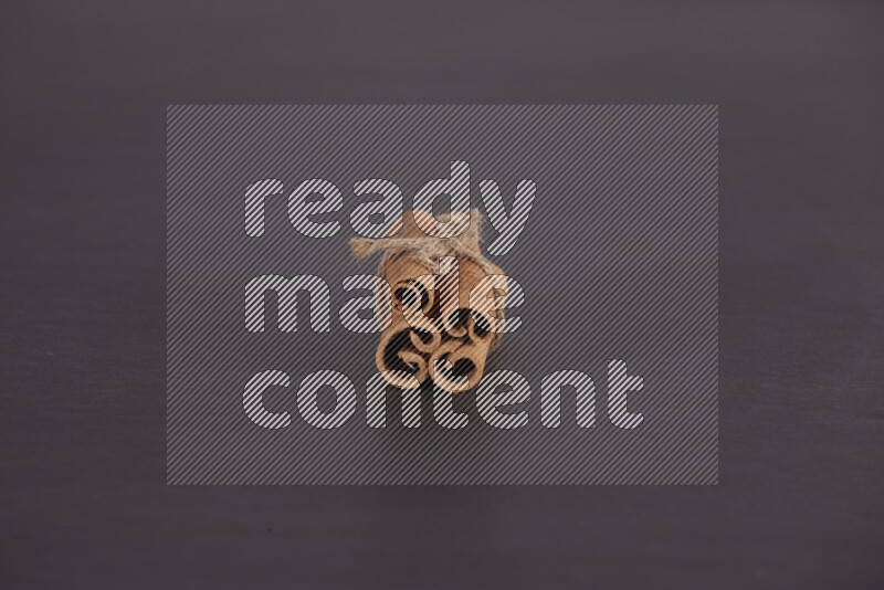 4 Cinnamon sticks stacked and bounded on black flooring