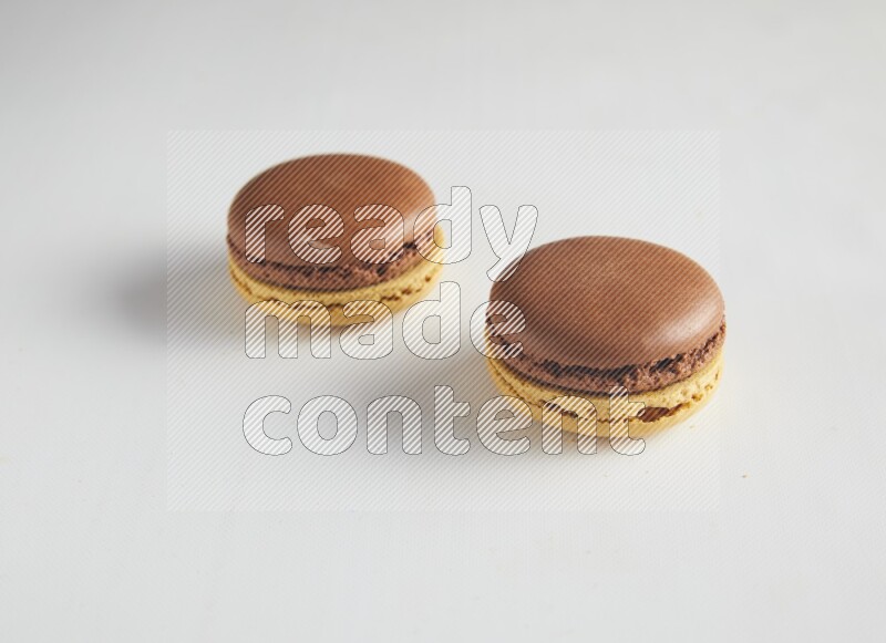 45º Shot of two Yellow and Brown Chai Latte macarons on white background