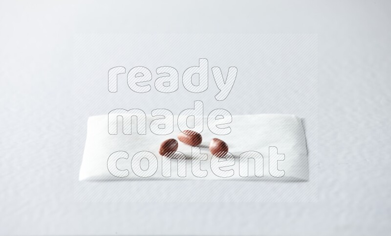 3 red skin peanuts on a piece of paper on a white background in different angles