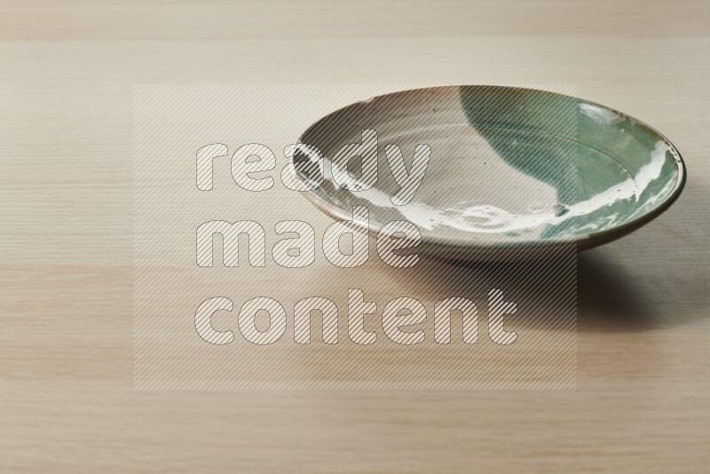 A multicolored pottery plate on light wooden background