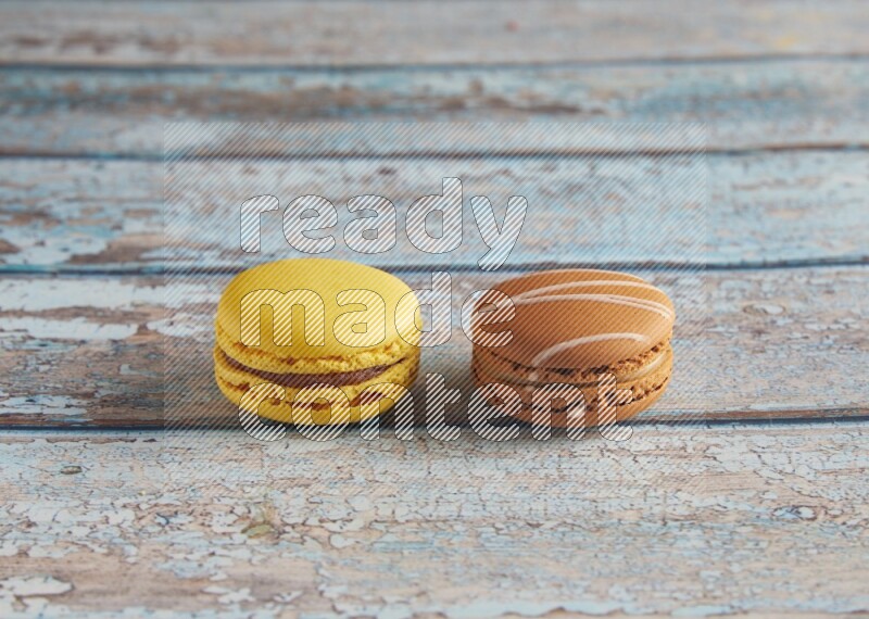 45º Shot of of two assorted Brown Irish Cream, and Yellow Lemon macarons on light blue background
