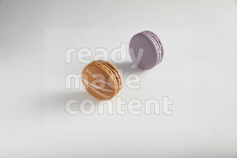 45º Shot of of two assorted Brown Irish Cream, and Purple Blueberry macarons on white background