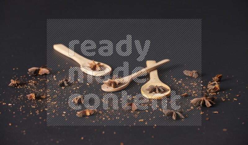 Star Anise in wooden spoons on black flooring
