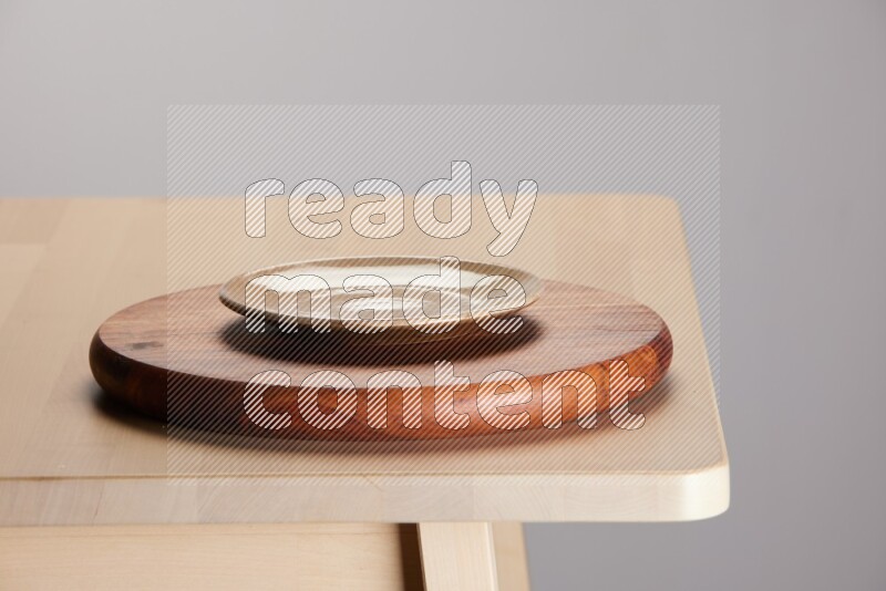 multi-colored pottery Plate placed on a dark colored wooden tray on the edge of wooden table