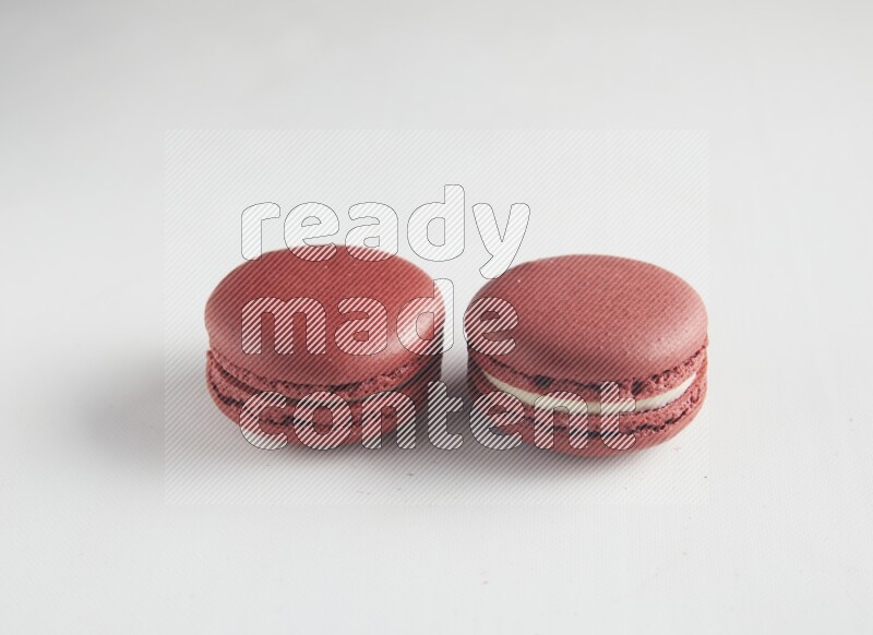 45º Shot of two Red Velvet macarons on white background