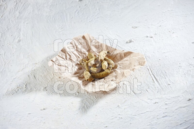 Dried turmeric whole fingers in a crumpled piece of paper on textured white flooring