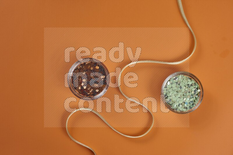A green and orange collection of sewing and tailoring tools arranged on a orange background