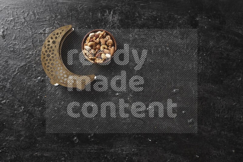 Nuts in a wooden bowl with a wooden lantern in a dark setup