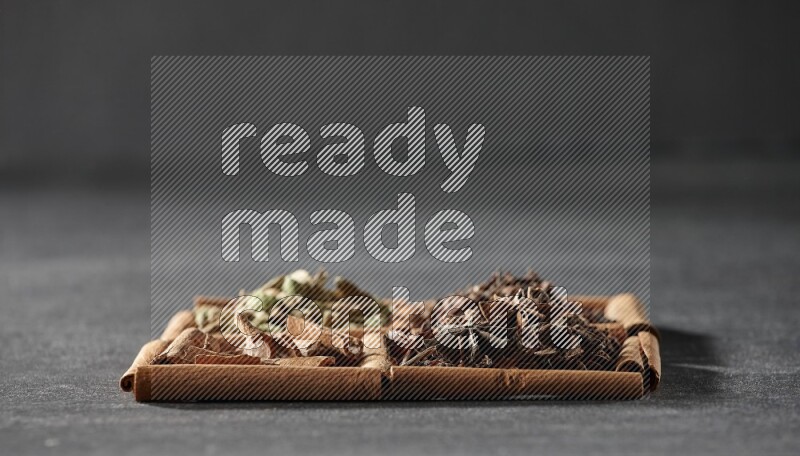 4 squares of cinnamon sticks full of cinnamon, cardamom, cloves and star anise on black flooring