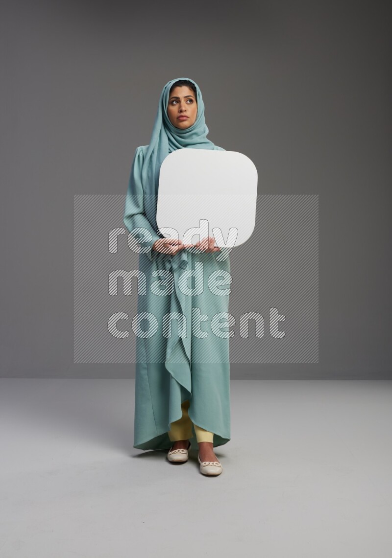 Saudi Woman wearing Abaya standing holding social media sign on Gray background