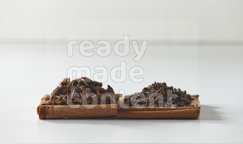2 squares of cinnamon sticks full of cloves and star anise on white flooring