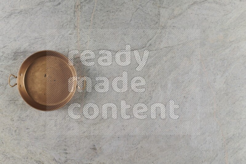 A small copper pan on grey marble background