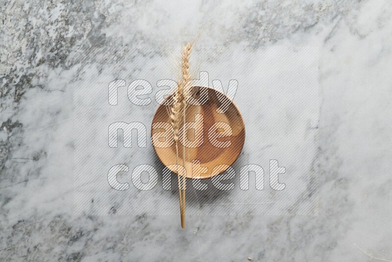 Wheat stalks on multicolored pottery plate on grey marble background