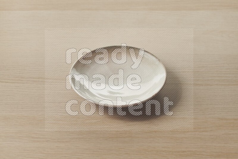 A beige pottery plate on light wooden background