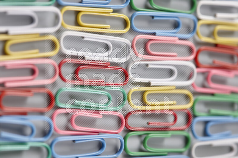 Multicolored paper clips isolated on a grey background