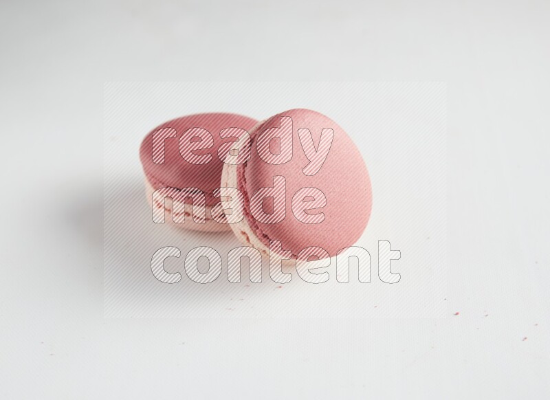 45º Shot of two Pink Litchi Raspberry macarons on white background