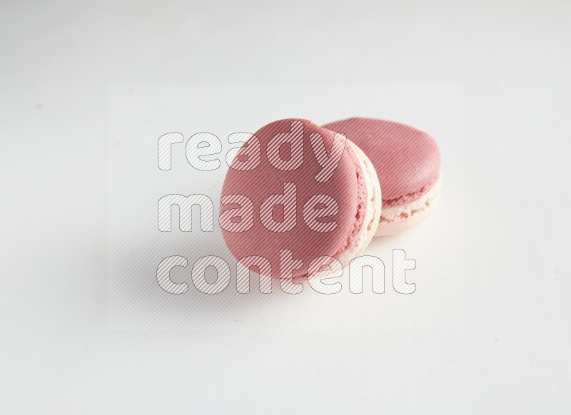 45º Shot of two Pink Litchi Raspberry macarons on white background
