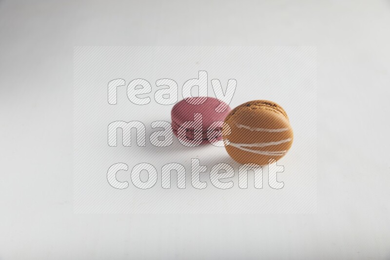 45º Shot of of two assorted Brown Irish Cream, and Red Cherry macarons on white background