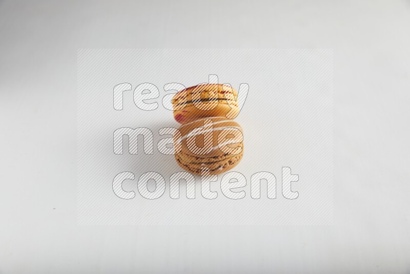 45º Shot of of two assorted Brown Irish Cream, and Orange Exotic macarons on white background