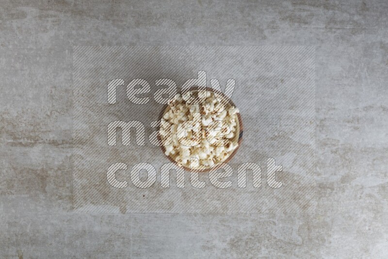 popcorn in wooden bowl on a grey textured countertop