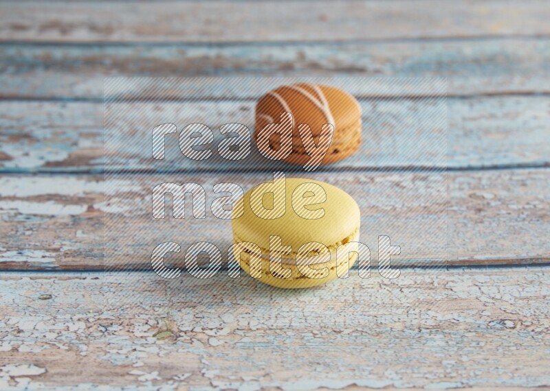 45º Shot of of two assorted Brown Irish Cream, and Yellow Lime macarons on light blue background