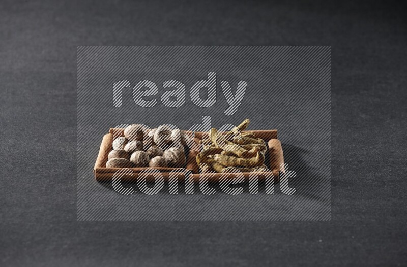 2 squares of cinnamon sticks full of nutmeg and turmeric fingers on black flooring