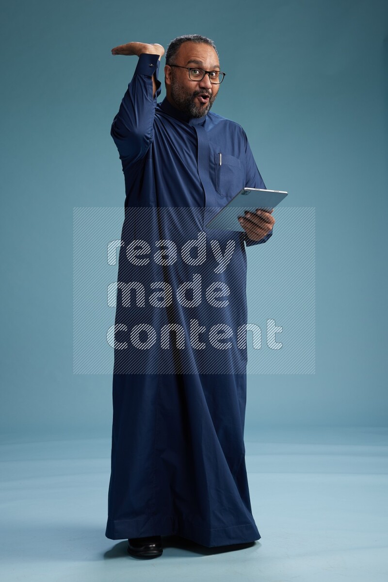Saudi Man without shimag Standing working on tablet on blue background