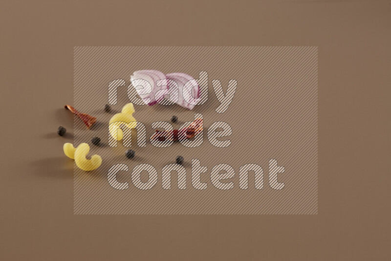 Raw pasta with different ingredients such as cherry tomatoes, garlic, onions, red chilis, black pepper, white pepper, bay laurel leaves, rosemary and cardamom on beige background