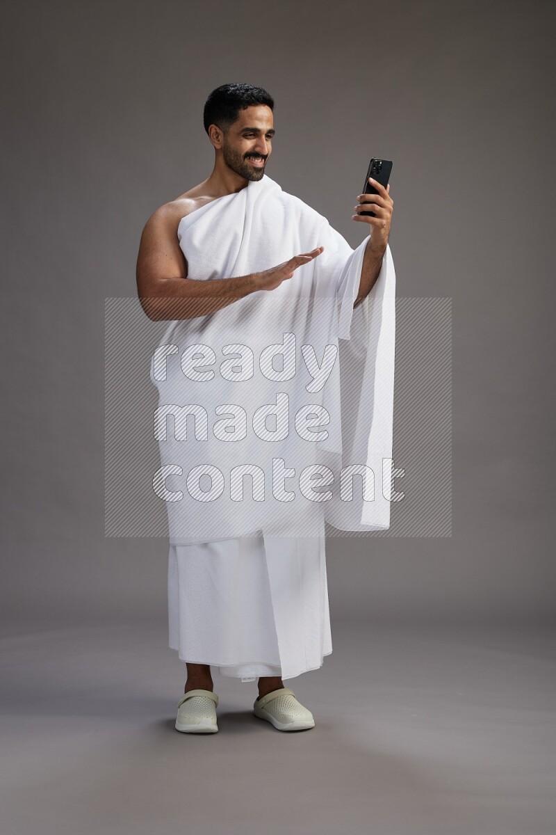 A man wearing Ehram Standing taking selfie on gray background