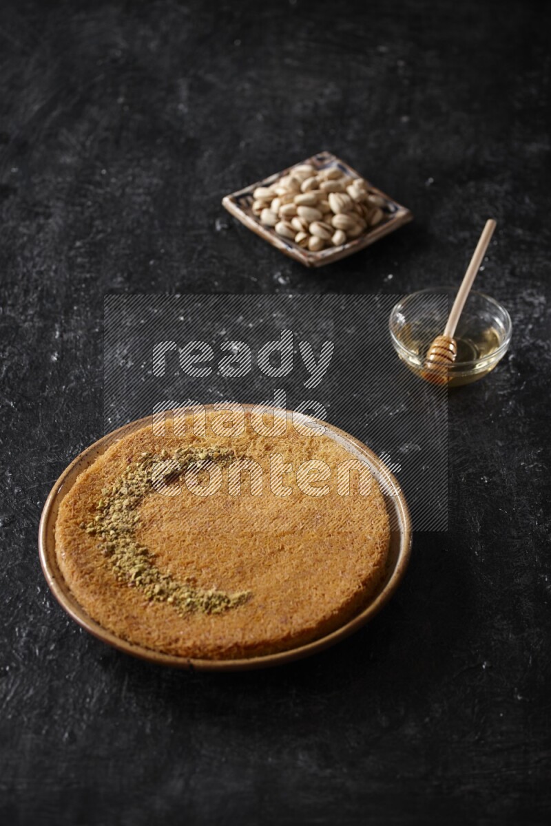 Konafa with nuts and honey in a dark setup