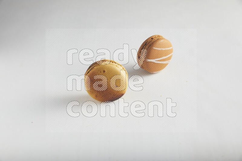 45º Shot of of two assorted Brown Irish Cream, and Yellow Crème Brulée macarons on white background