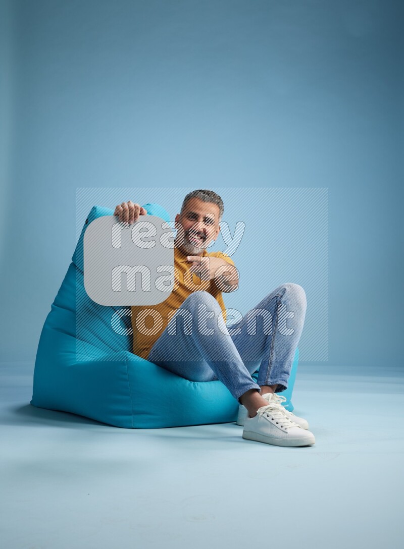A man sitting on a blue beanbag and holding social media sign