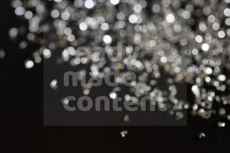 Silver shimmering fragments of glass scattered on a black background