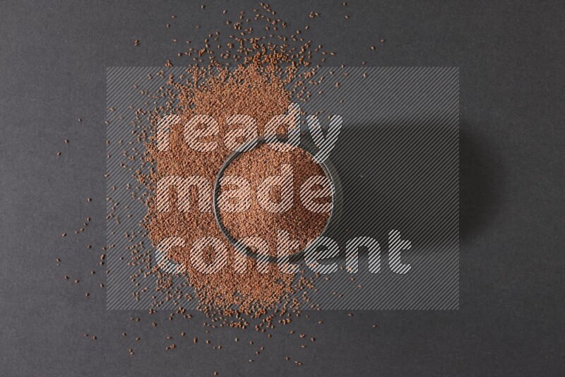 وعاء فخاري أسود ممتلئ ببذور حب الرشاد محاط بالبذور على أرضية سوداء