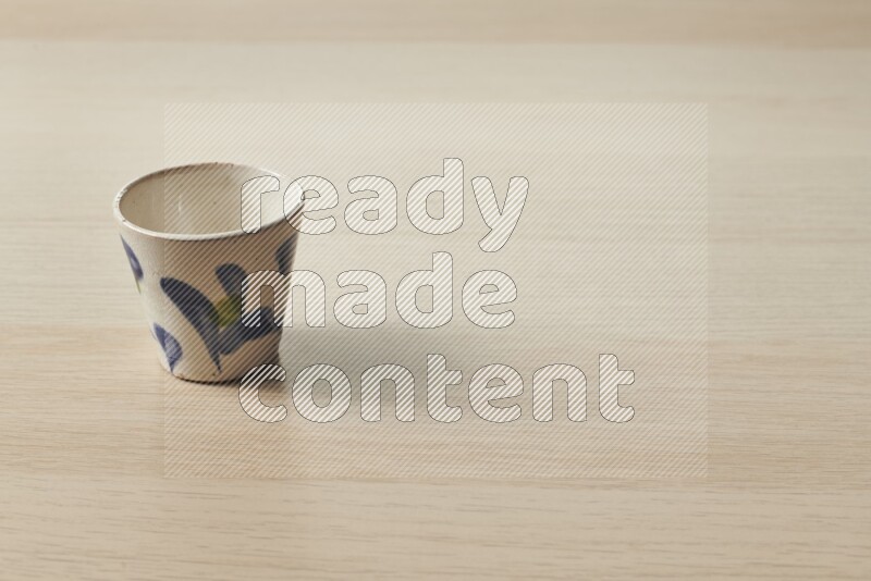A pottery cup on light wooden background