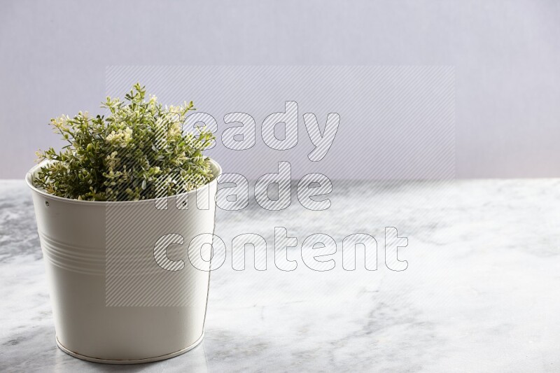 Artificial plant in white pot on grey marble background