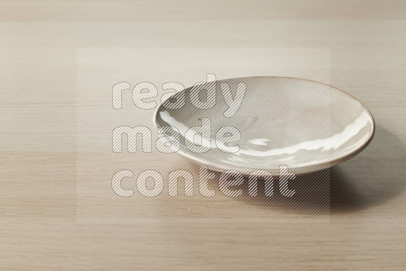 A beige pottery plate on light wooden background