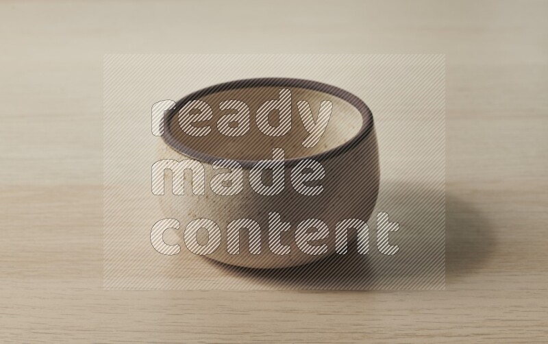 A beige pottery oven bowl on light wooden background