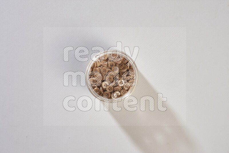 Colored buttons in a glass jar on grey background