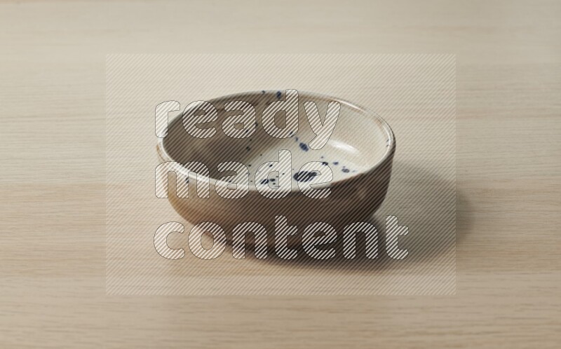 A multicolored pottery bowl on light wooden background