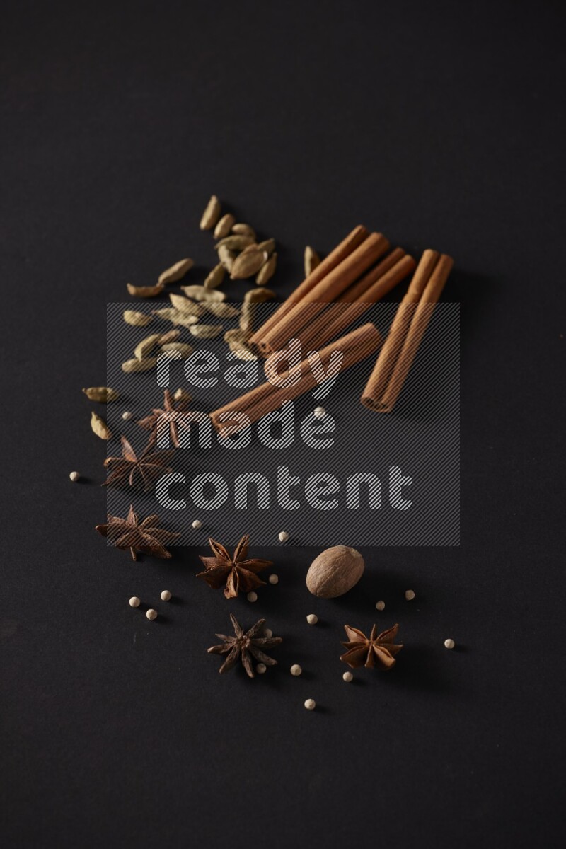Cinnamon sticks, cardamom, star anise, nutmeg and white peppers on a black background