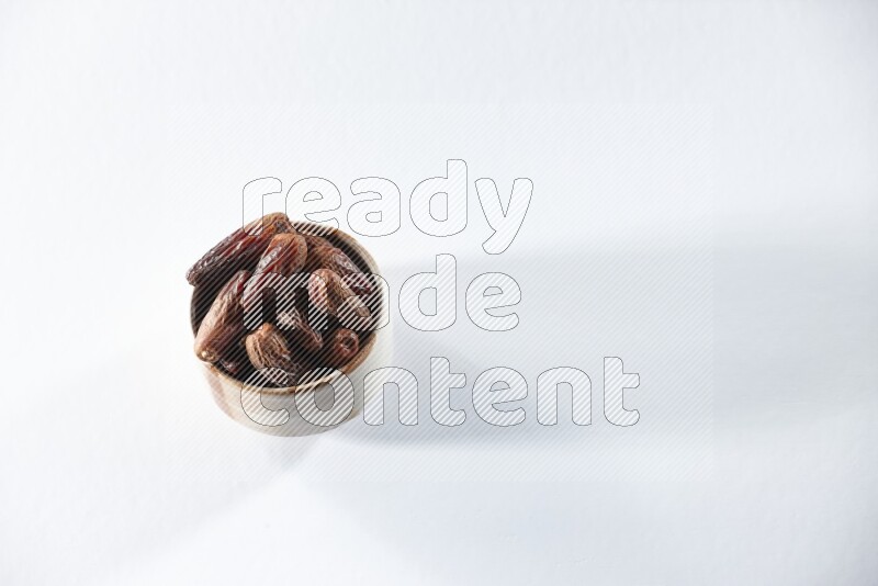 A beige ceramic bowl full of dried dates on a white background in different angles